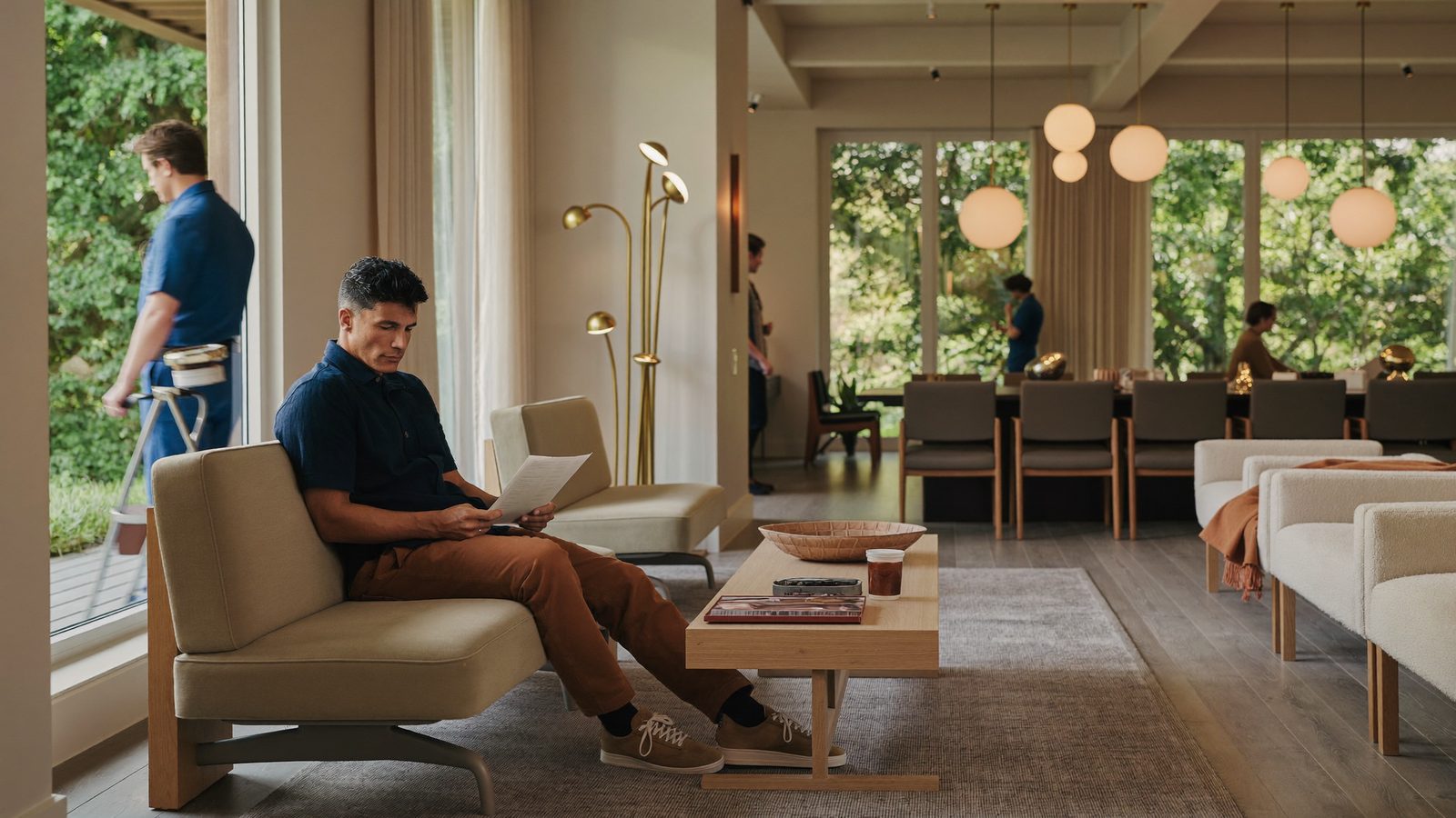 Man reviewing a printed treatment plan on a sofa in a calm, modern clinic lounge with large windows