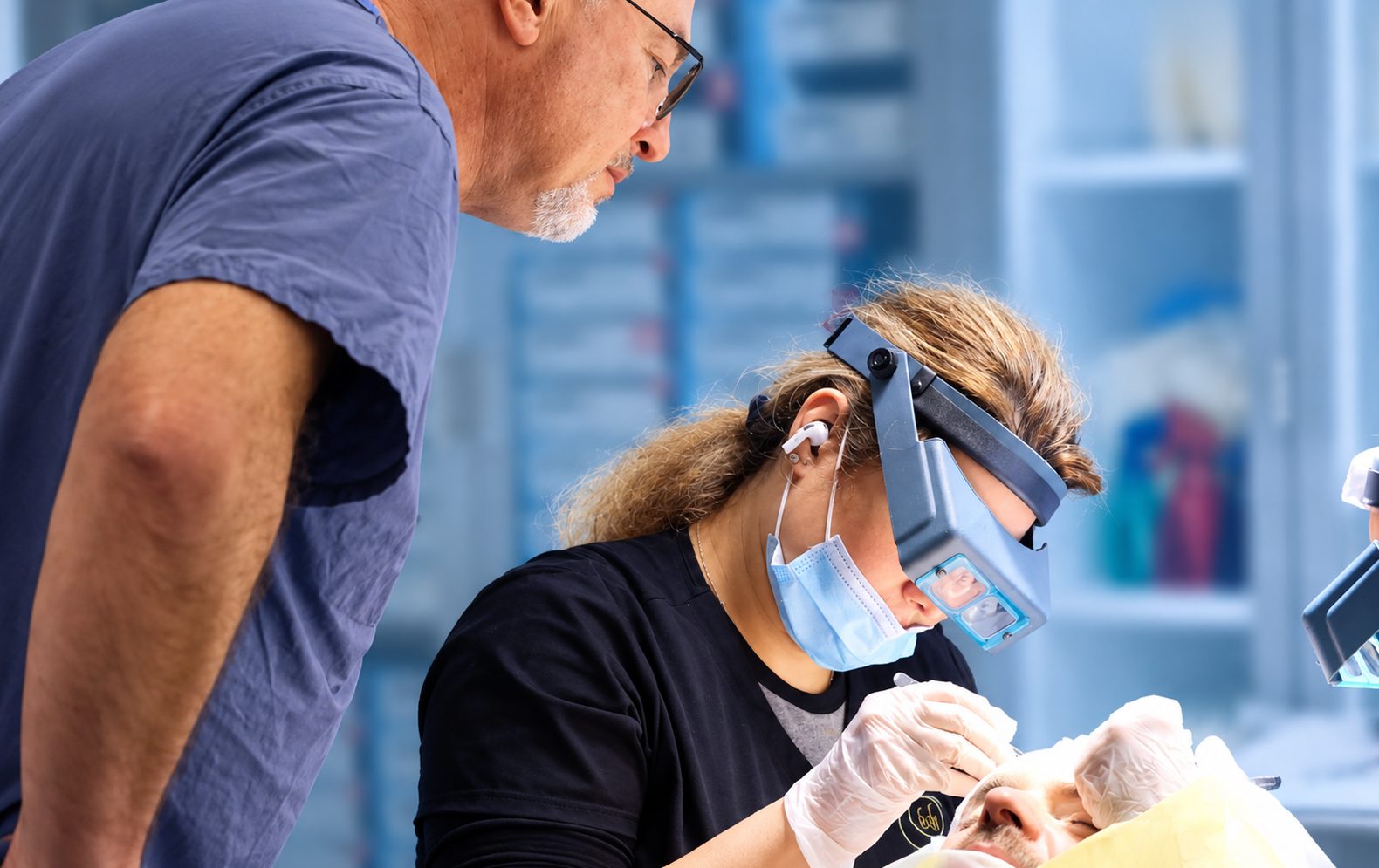 Technician placing grafts under magnifying loupes while Dr. Val Prokurat, MD looks on during an FUE procedure at Nova Medical NYC